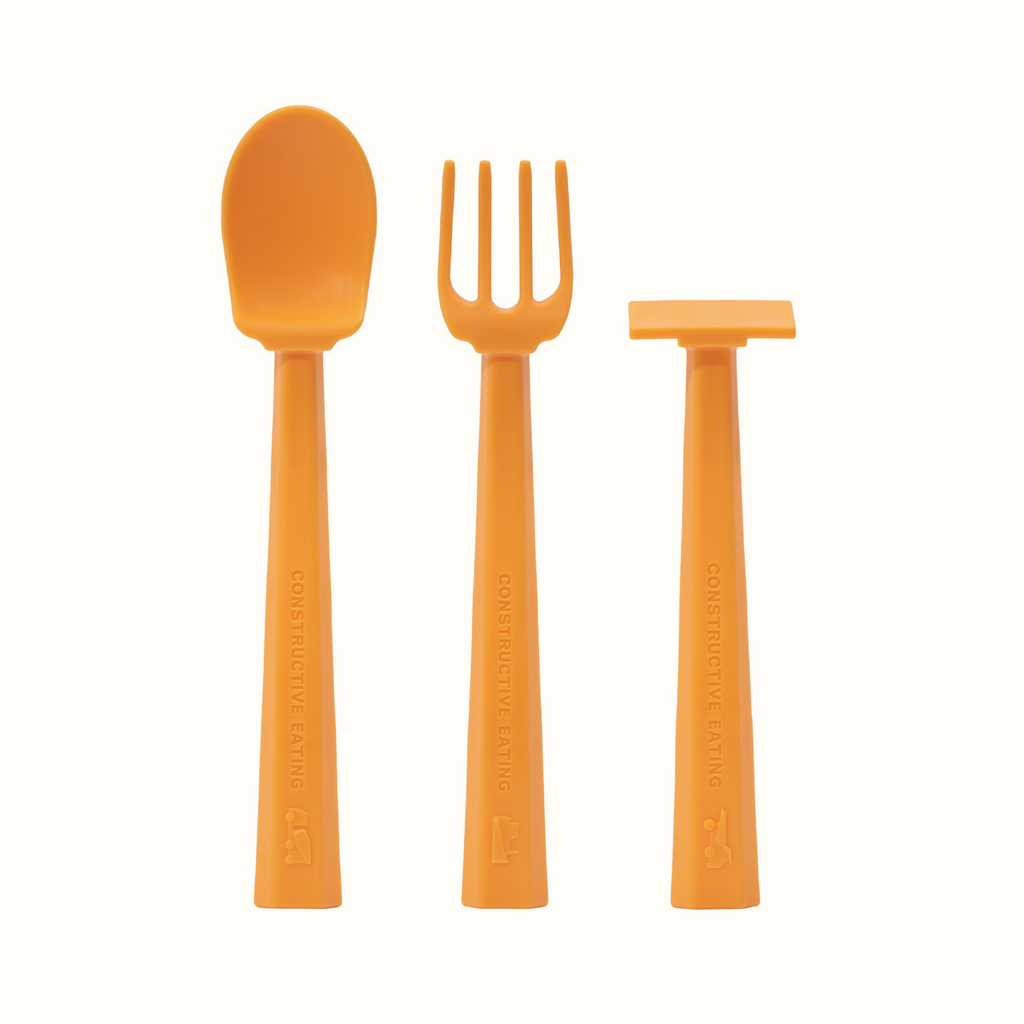 Image of the orange training utensils. The utensils included are a pusher, fork, and spoon.