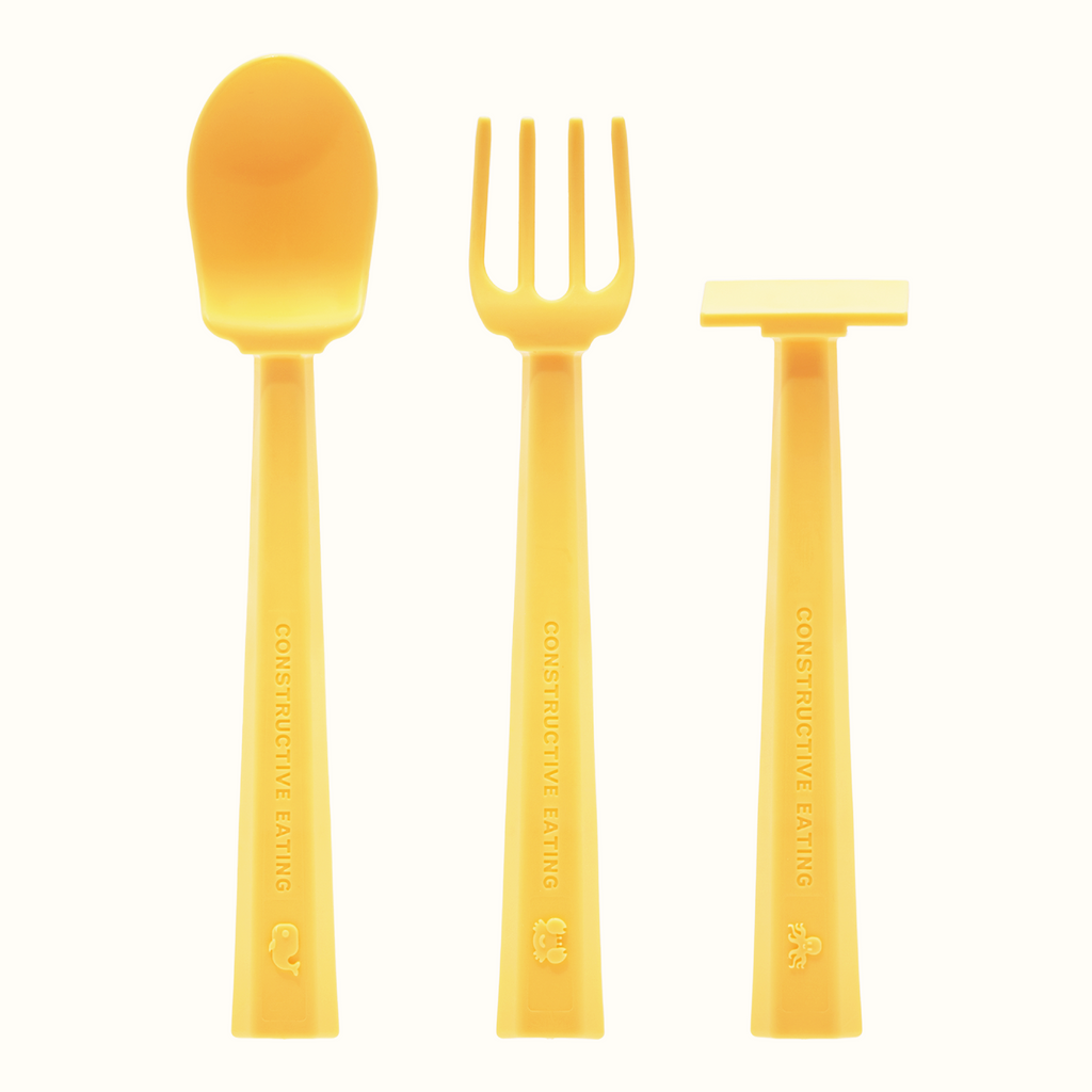 Image of the Training Utensils in a vertical position. The sunshine yellow utensils include a pusher, fork , and spoon. There's a small detail of a whale on the spoon handle, a crab on the fork handle, and an octopus on the pusher handle.