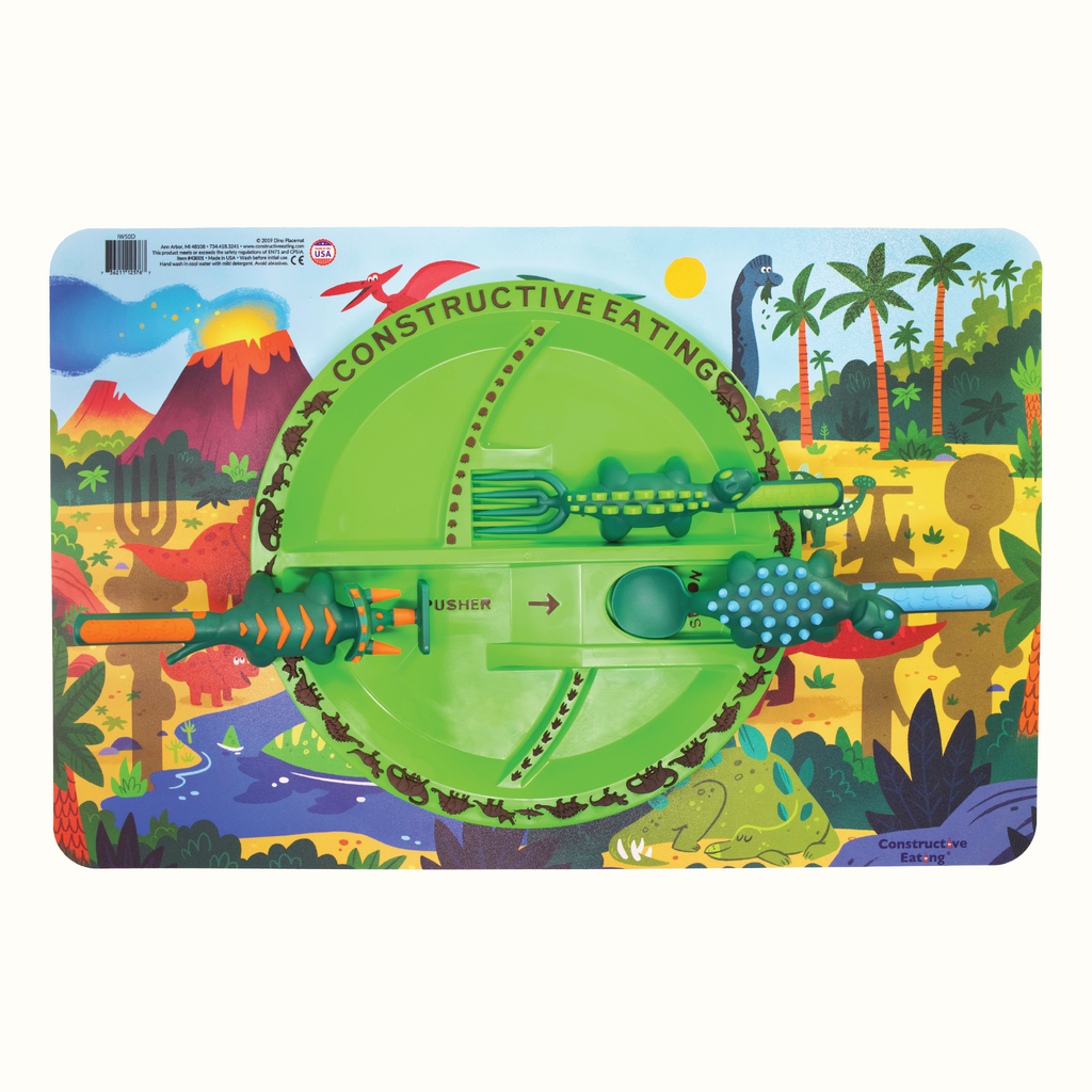 Image of the Dino Fan Bundle. The image includes the Dino Utensils, Plate, and Placemat. The Dino Pusher is in the shape of a triceratops, the Dino Fork is in the shape of a stegosaurus, and the Dino Spoon is in the shape of an ankylosaurus. The Dino Plate is green and dino placemat features a jurassic landscape.