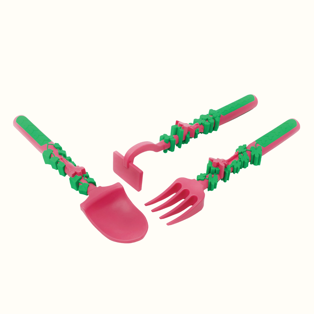 Image of the Garden Fairy Utensils angled. The pink utensils include a garden hoe pusher, a garden rake fork, and a garden shovel spoon.