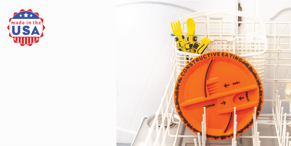 Image of the yellow construction utensils and orange plate in the dishwasher demonstrating that all our plates and utensils are dishwasher safe. The utensils included are a bull dozer pusher, a fork lift fork, and a front loader spoon. Also shown is a red, white, and blue logo stating our products are all Made in the USA.