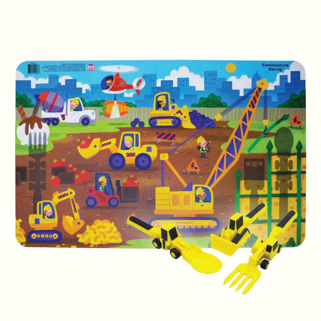 Image of the Construction Utensils and Construction Placemat. The yellow utensils include a bull dozer pusher, a fork lift fork, and a front loader spoon.  The Placemat illustrates a construction worksite with construction vehicles working with food such as mac & cheese, blueberries, and ice cream.