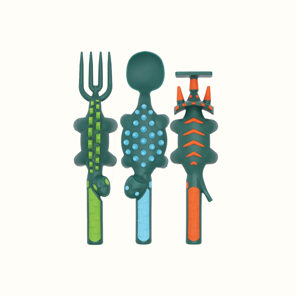 Image of the Dino Utensils in a vertical position. The Dino Pusher is in the shape of a triceratops, the Dino Fork is in the shape of a stegosaurus, and the Dino Spoon is in the shape of an ankylosaurus.