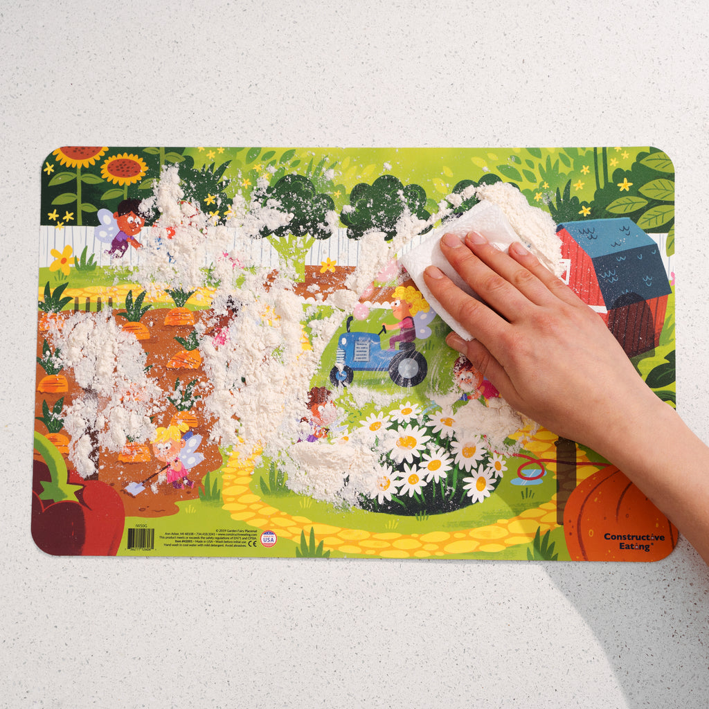 Image of the Garden Fairy Placemat covered in flour with someone using a paper towel to wipe the surface clean.